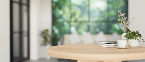 A space for display products on a minimalist round wooden table in a contemporary white living room.