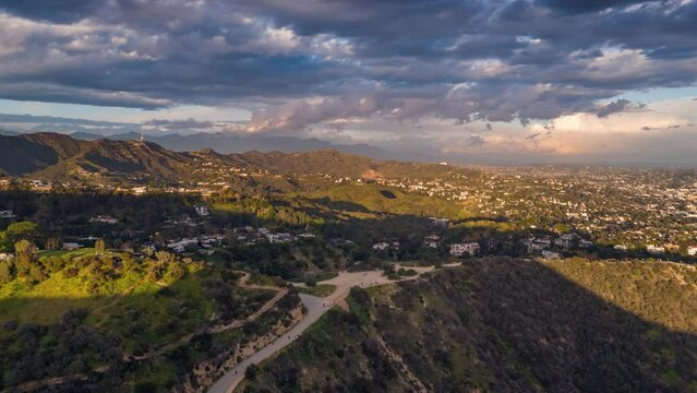Aerial hyperlapse view of Hollywood hills panorama revealing city of Los Angeles skyline, shot during golden hour right before sunset.