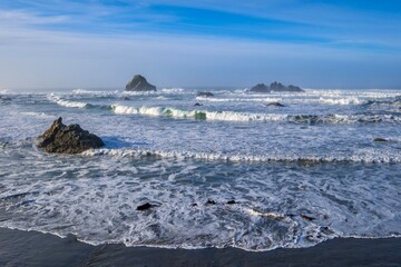 Bandon beach in high tide with waves and white foam. Seastacks in the ocean. Oregon. USA