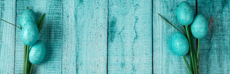 Happy easter banner. Colored Easter eggs on a pastel blue wooden background