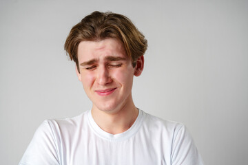 Young Man With Brown Hair Expressing Sadness Against a Plain Background