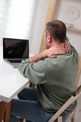 Man with neck pain while working on a laptop.