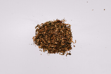 Brown colored cigarette tobacco with a slightly wet texture is ready to be made into several cigarettes for mixing.