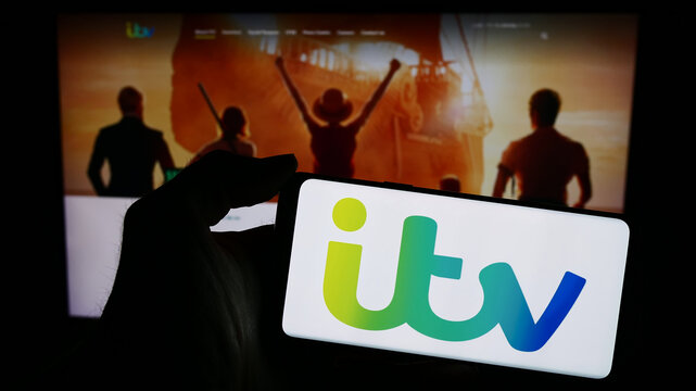 Stuttgart, Germany - 03-23-2024: Person holding smartphone with logo of British media and broadcasting company ITV plc in front of website. Focus on phone display.