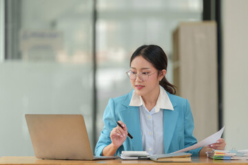 Businesswoman wearing glasses sits and works with documents Work files to search and review in...