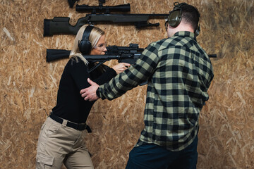 A blonde girl is training to shoot a rifle ar15 at a shooting range with an instructor.