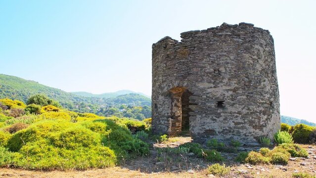 Watchtower tower ruins at Perdiki village on Ikaria island, Greece cityscape of small town with houses at longevity blue zone panning shot