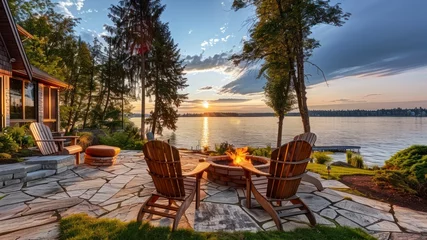  The Idyllic Backyard of a Waterfront House, Complete with Adirondack Chairs and a Fire Pit, Overlooking the Water © Gasspoll
