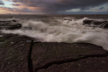 Tunelboka beach in Getxo, Bizkaia on a sunset with clouds and dramatic sky and with the sea beating the rocks of the coast