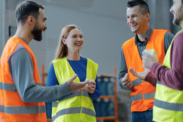 Group of workers wearing workwear holding cup with coffee talking, coffee break together in warehous