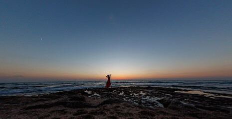 beautiful sensual woman in a red long dress posing on the seashore during sunset. beautiful sunset. - 776957167