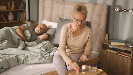Senior woman taking medicine in bedroom