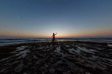 beautiful sensual woman in a red long dress posing on the seashore during sunset. beautiful sunset. - 776957752