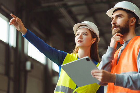 Successful, retired woman working with her foreman, gesturing while standing in a warehouse