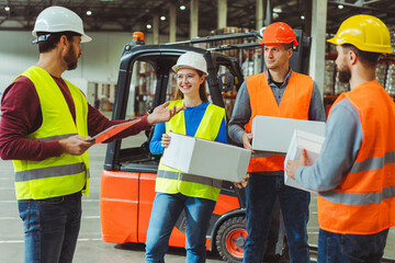 Group of workers wearing hard hats holding boxes, mockup listening manager working in warehouse