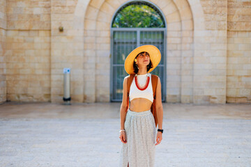A young girl in a hat and with a backpack walks among old buildings. travel and adventures in Israel. Haifa. - 776960553