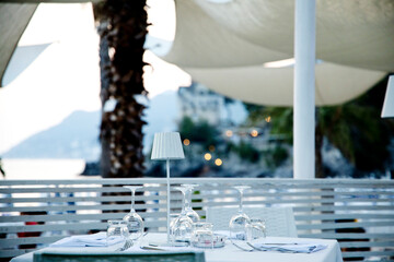 glasses arranged on a table with the Amalfi coast and palm trees in the background