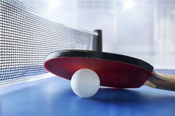 Ping-pong paddle resting on ball on table in sports hall