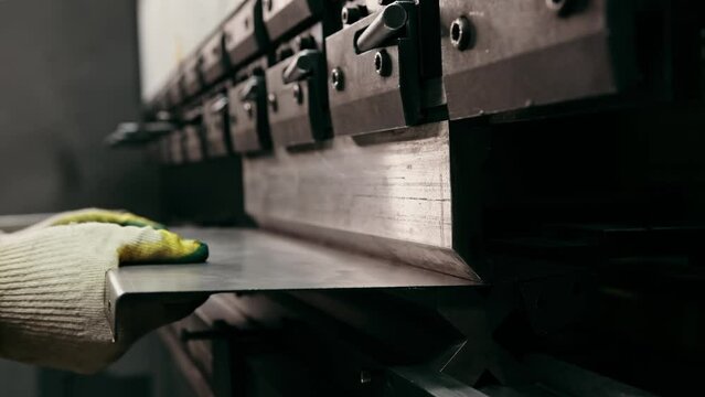 Plate steel worker hands put of industrial bending machine metal press industry equipment factory. Worker holds steel sheet on bending machine forms steel products. Bending metal machine. Metalworking