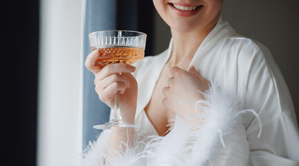 Happy young woman bride with champagne celebrating wedding day, morning