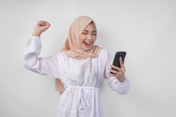 Young Asian Muslim woman with a happy successful expression wearing white dress and hijab holding...
