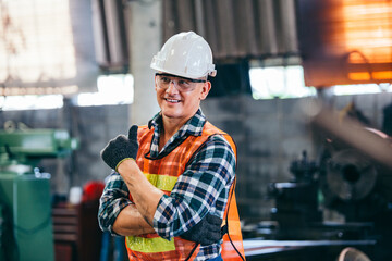 Portrait of male foreman factory wearing hardhat in arms crossed and showing thumb up looking at...