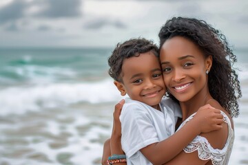 portrait of smiling african american mother and son enjoying sunny day at beach. unaltered, family, lifestyle, togetherness, enjoyment and holiday concept