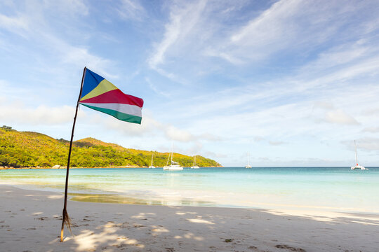 The flag of Seychelles stands on the beach