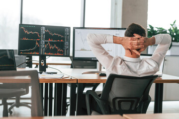 Rear view. Businessman is sitting by computer and working in the office