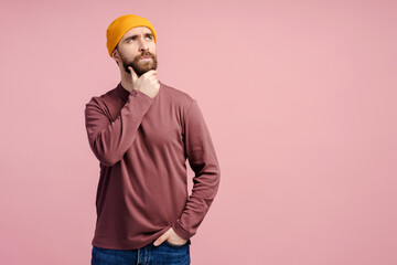 Handsome serious bearded man wearing yellow hat looking away isolated