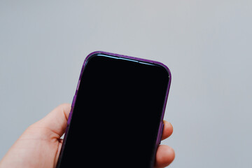 A smartphone with a blank black screen in his hand. A place for an inscription or image. modern...