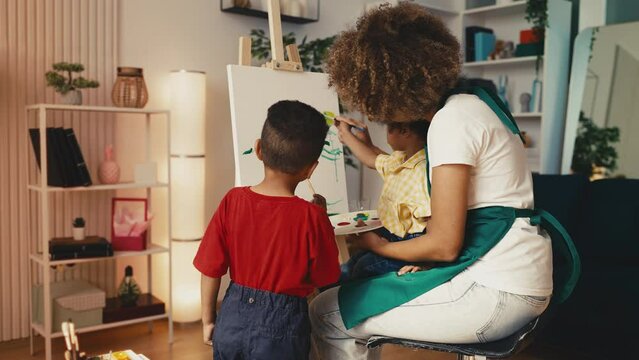 African American mom and little sons painting a picture together, creative hobby