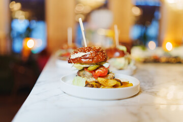 A classic American dish of a hamburger and french fries served on a plate with tableware, a staple food in Western cuisine, made with ingredients like beef, potatoes, and condiments