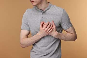 Man suffering from heart hurt on beige background, closeup