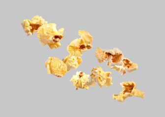 Tasty fresh popcorn flying on grey background