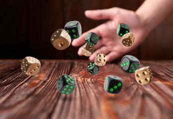Woman throwing many dice on wooden table, closeup