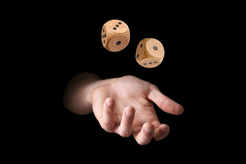 Man throwing wooden dice on black background, closeup