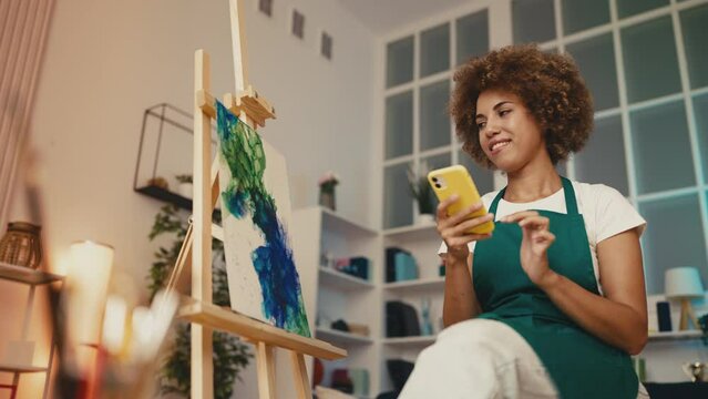 Happy female painter taking photo of own picture, selling her art work online
