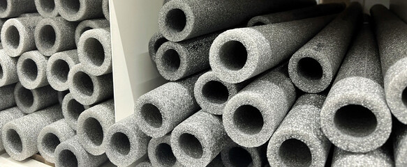 Stacks of grey foam insulation tubes for pipes in a store. International Repair Day. World Plumber Day
