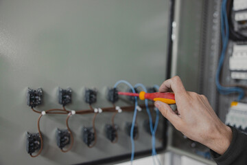 Electrician fixing a fuse box with a screwdriver. Electrical Installation or Repair, cable wiring...