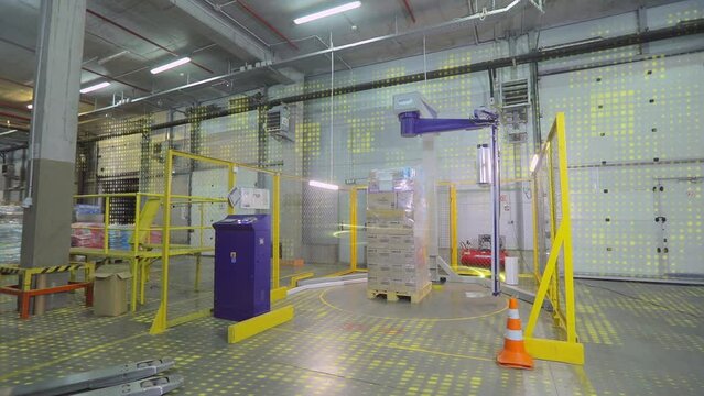 Packaging boxes with products in plastic film at the factory. A special machine wraps boxes in polyethylene film
