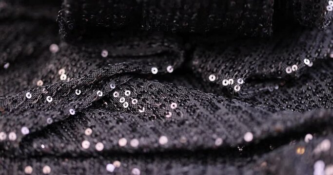 a large number of sequins on a black material, a part of the black material decorated with plastic discs to create shine