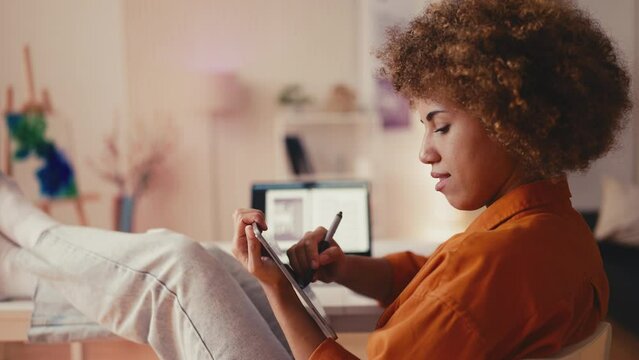 Inspired woman designer creating logos on graphic tablet at home office