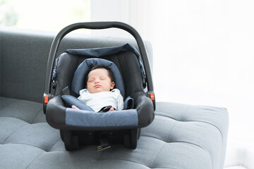 Portrait of adorable less than one month old newborn baby girl sleeping in the modern car seat with...