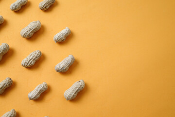 Top view of fresh peanuts in shells in row on yellow background with copy space