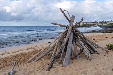 Fototapeta na wymiar A bundle of driftwood is stacked and ready for a bonfire on Shipwreck Beach in Koloa, Hawaii.