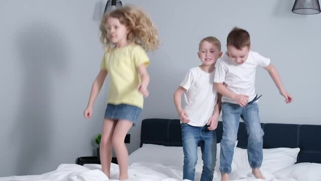 Portrait of children happily jumping on the bed of their parents' bedroom. little boys and girl, brothers and sister having fun and laughing, happy children.