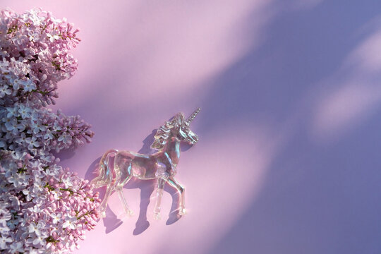 lilac flowers and crystal unicorn on violet background. Magic Crystal Ritual, Witchcraft. unicorn - Mystical symbol of awakened consciousness, integrity, peace, prudence, purity, chastity. top view