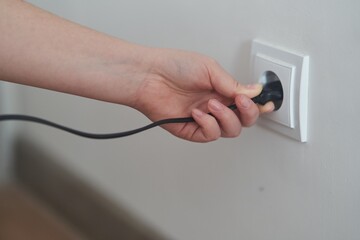 A young girl inserts a plug into an outlet. Young woman plugs the phone charger into the socket. High quality photo