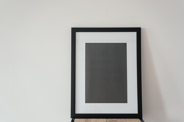 Blank wooden photo frame stands in the interior on a white background. Mockup poster frame close up in home interior.